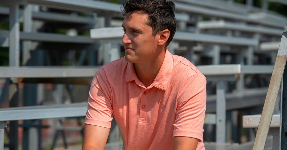 Ricky Andrade, self-made forex trading millionaire and founder of Market Masters Academy, looking thoughtful in a pink polo shirt