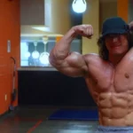 Sam Sulek flexing his muscular physique in a gym, showcasing the physique that helped build his multi-million dollar net worth as a fitness influencer