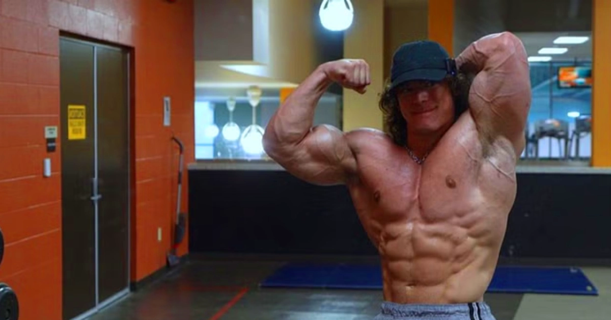 Sam Sulek flexing his muscular physique in a gym, showcasing the physique that helped build his multi-million dollar net worth as a fitness influencer