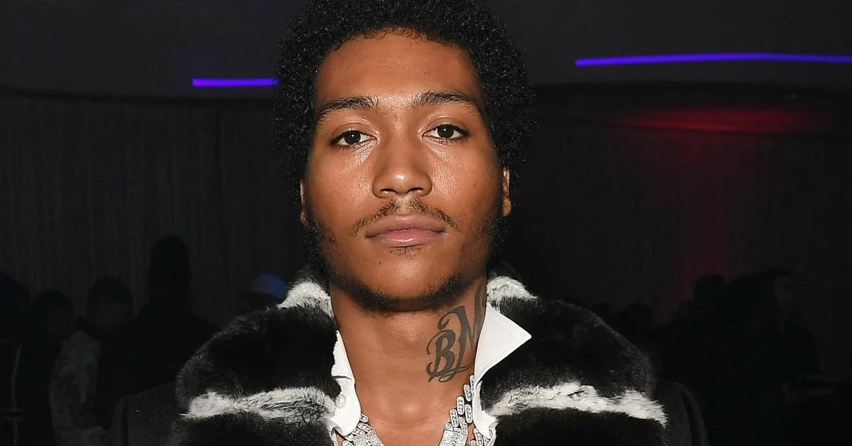 Lil Meech at an event, wearing a fur-collared coat and diamond chain, representing his success and Lil Meech Net Worth in 2025