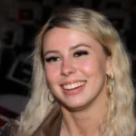 Young woman with blonde hair and hoop earrings smiling, related to Hawk Tuah viral star and her growing net worth