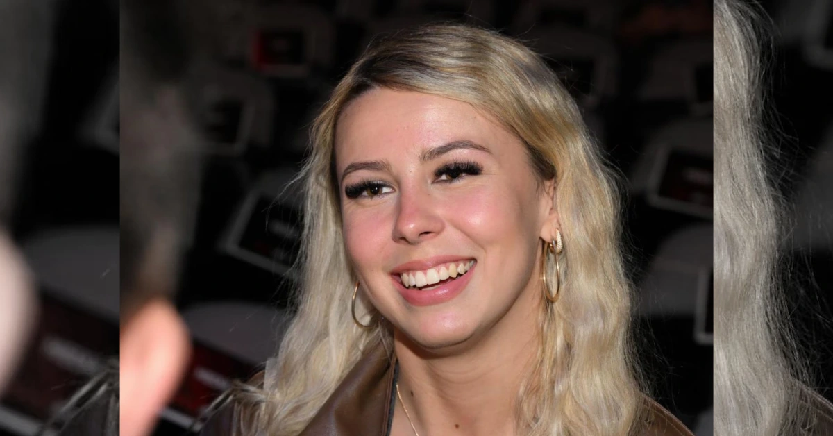 Young woman with blonde hair and hoop earrings smiling, related to Hawk Tuah viral star and her growing net worth