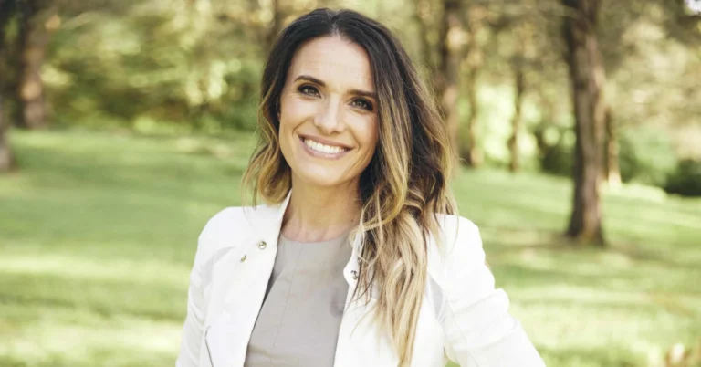 Rebecca St James smiling on stage with a microphone, representing her successful music career and highlighting Rebecca St James Net Worth.